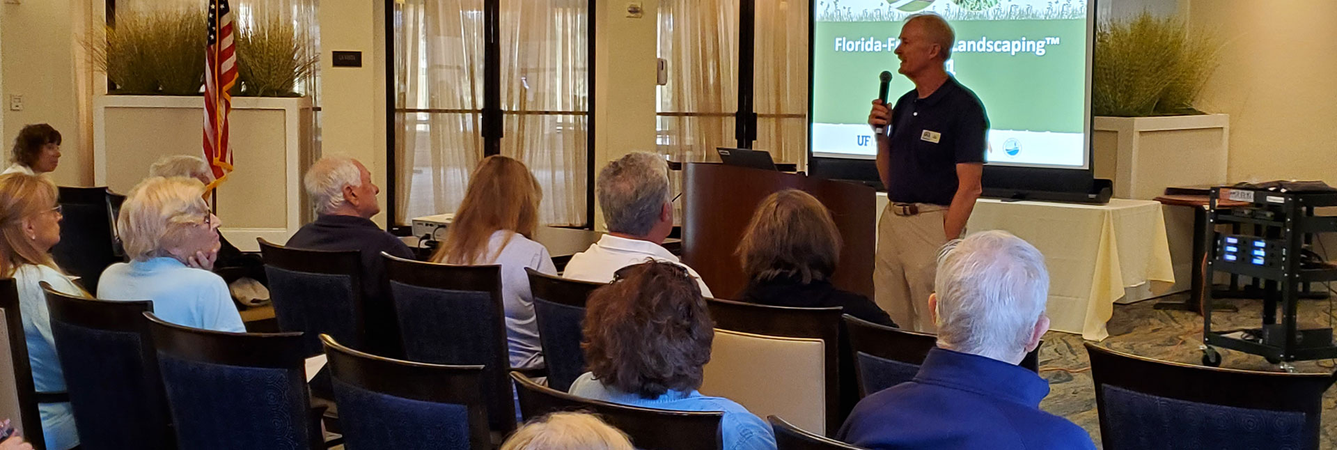 Man giving a presentation about Florida landscaping to a room full of people